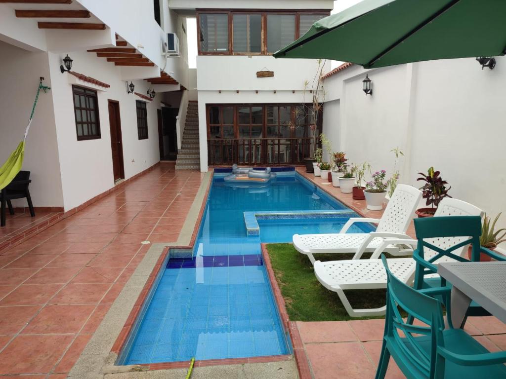 una piscina en medio de una casa con sillas y sombrilla en Casa en la playa, en Santa Elena