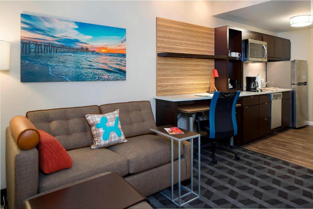 a living room with a couch and a desk and a kitchen at TownePlace Suites by Marriott Fort Myers Estero in Estero