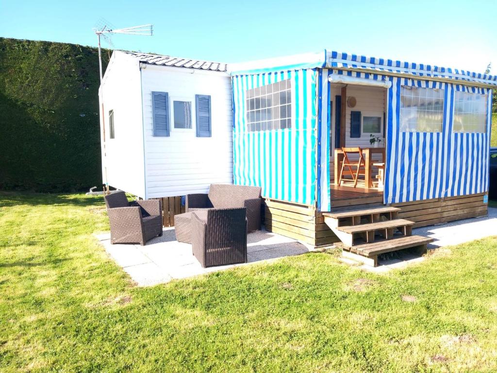 una casita azul y blanca en un patio en Bungalow, en Sainte-Marie-du-Mont