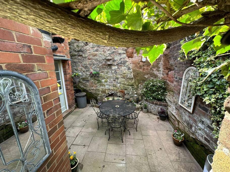 a patio with a table and chairs in a brick building at The Railway Cottage Bridgnorth in Bridgnorth