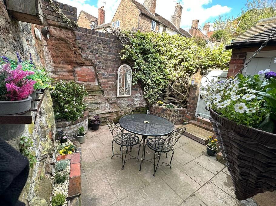 a patio with a table and chairs in a garden at The Railway Cottage Bridgnorth in Bridgnorth