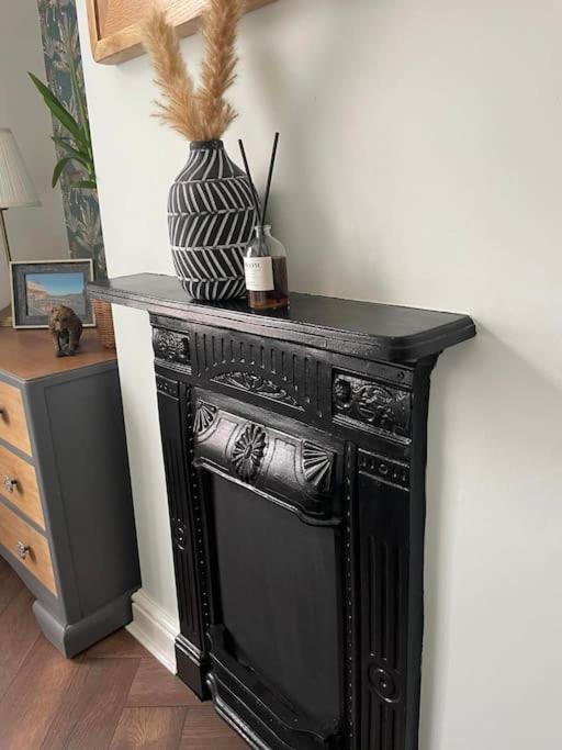 a black fireplace with a vase on top of it at The Railway Cottage Bridgnorth in Bridgnorth