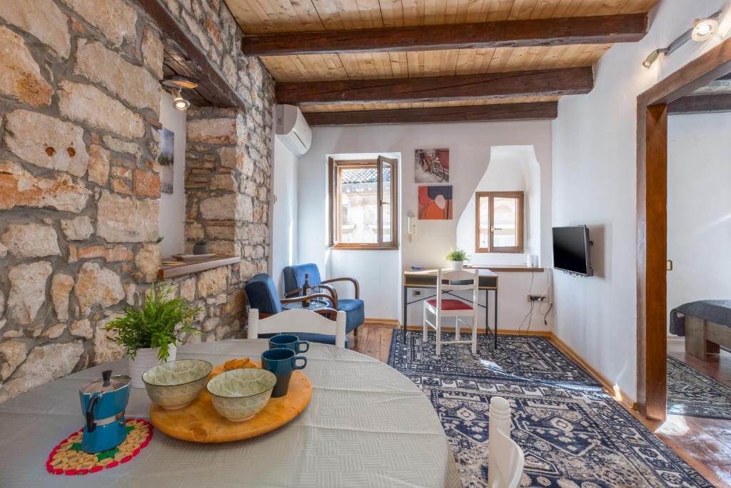a living room with a table and a stone wall at Apartment San Antonio in Rovinj