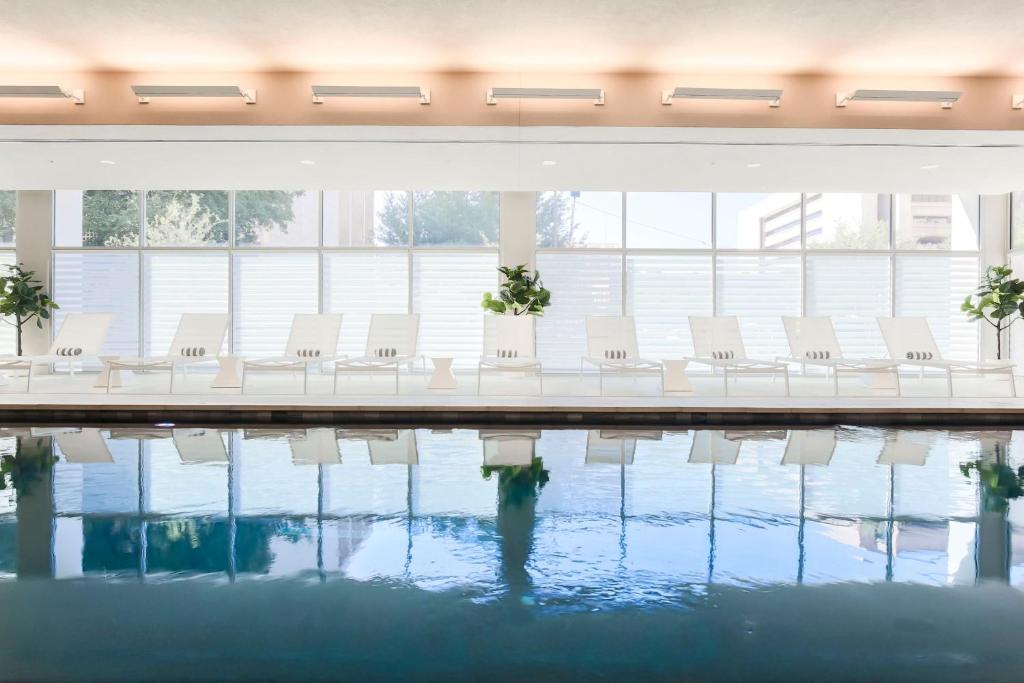 een rij witte stoelen naast een zwembad bij AC Hotel by Marriott Dallas Downtown in Dallas