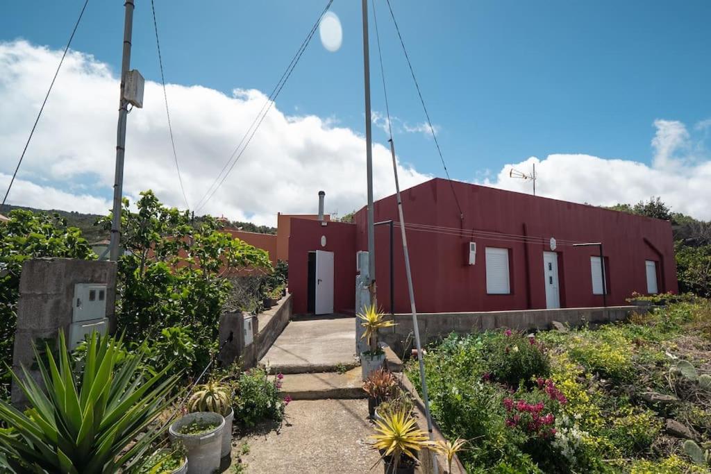 un edificio rojo en medio de un jardín en Casa el Monte, en San Juan del Reparo