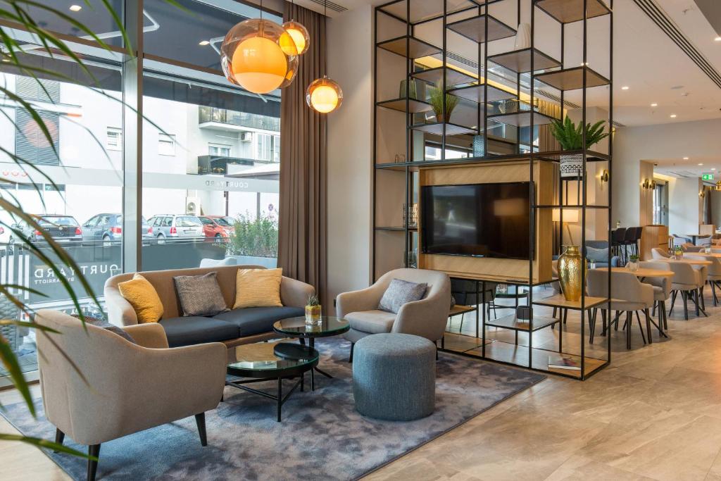 a lobby with couches and chairs and a television at Courtyard by Marriott Banja Luka in Banja Luka