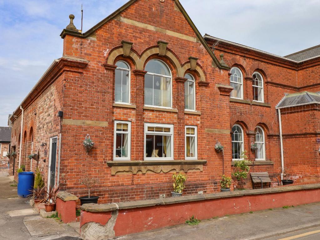 a red brick building with windows on a street at The Old Police House in Withernsea