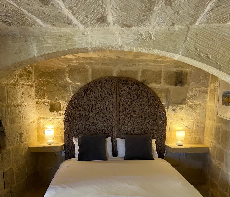a bedroom with a large bed in a stone wall at Razzett Ghasri in Għasri