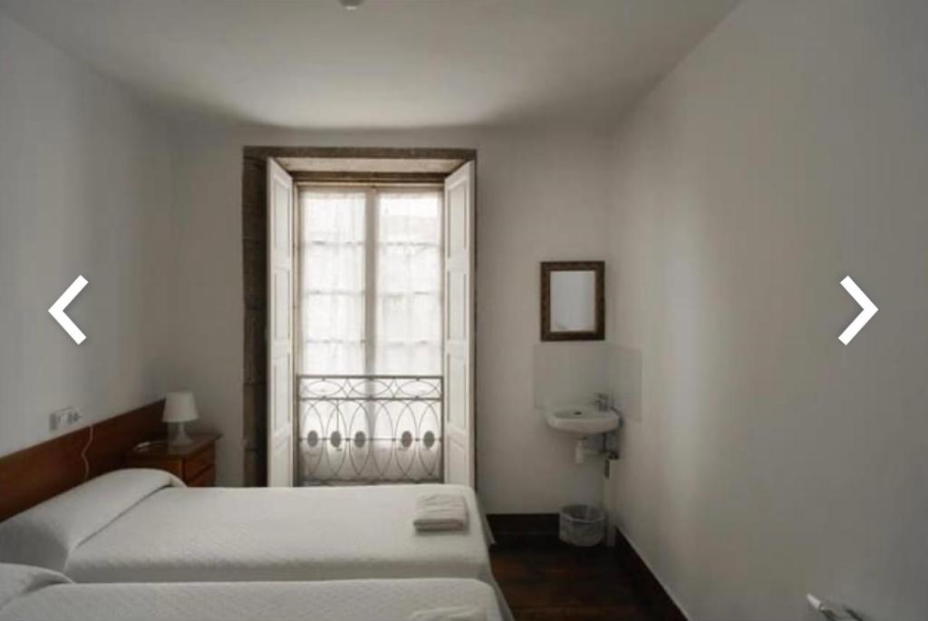 a bedroom with a bed and a window with two arrows at Casa Anglicana del Peregrino/ Pensión Santa Cristina in Santiago de Compostela