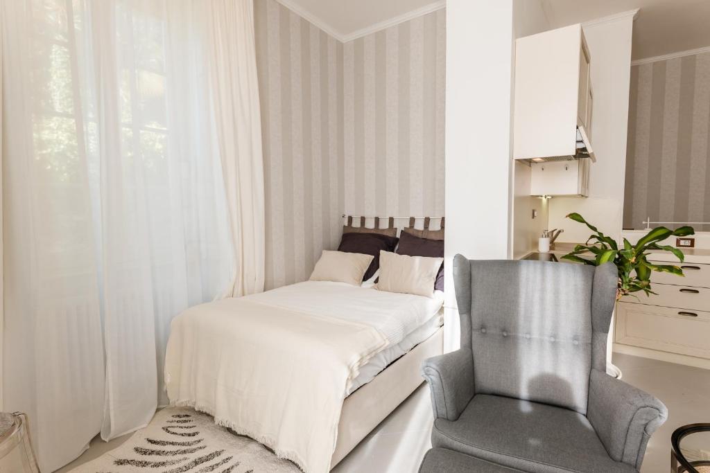 a white bedroom with a bed and a chair at Bella Belle Griante in Griante Cadenabbia