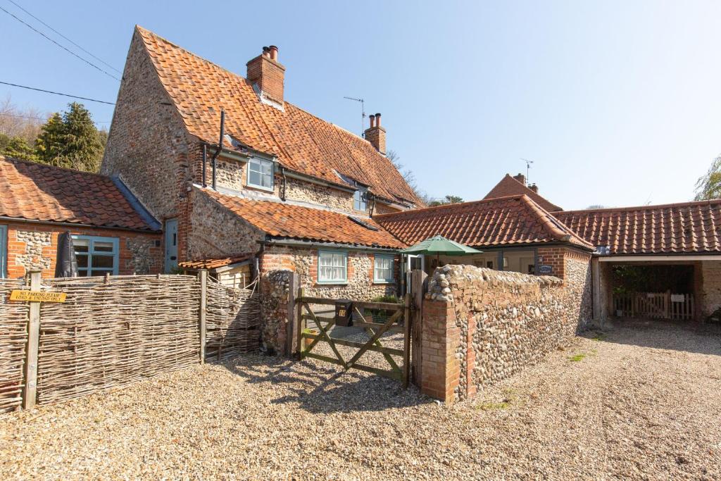 an old brick house with a fence in front of it at Lavender Cottage in Stiffkey