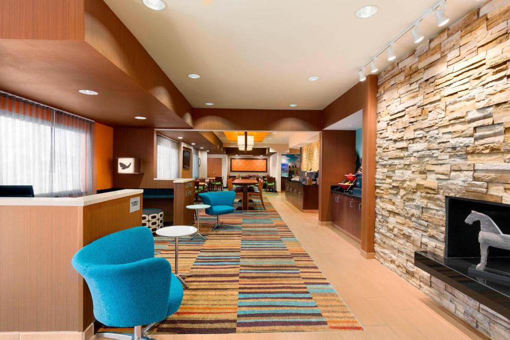 a lobby with a fireplace and blue chairs at Fairfield Inn & Suites Saginaw in Saginaw