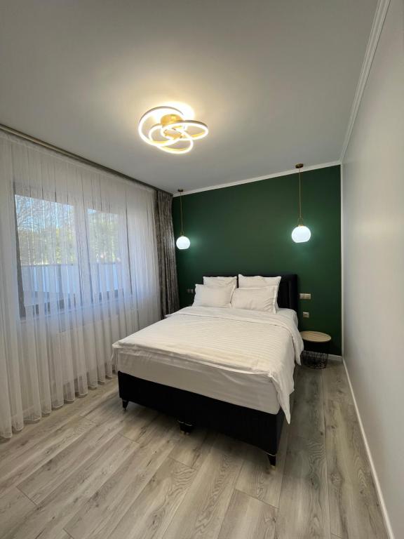 a bedroom with a large bed with a green wall at Glam Studios in Sibiu