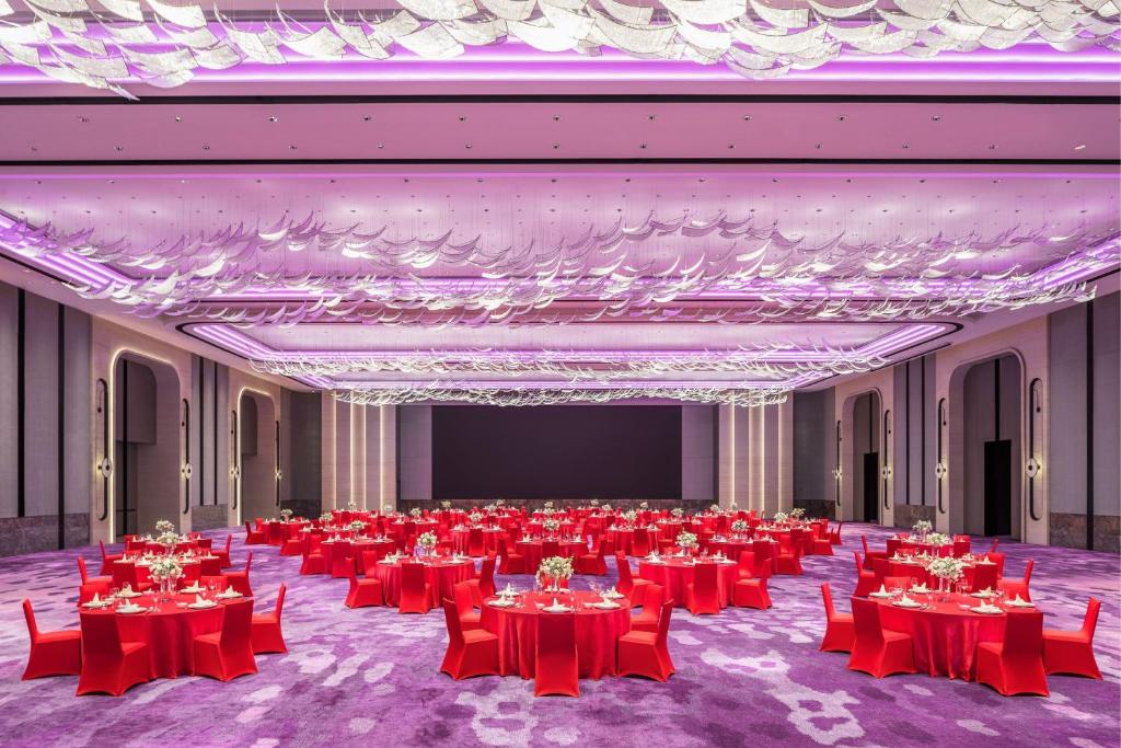 een grote feestzaal met rode tafels en stoelen bij Renaissance Zhuhai Hotel in Zhuhai