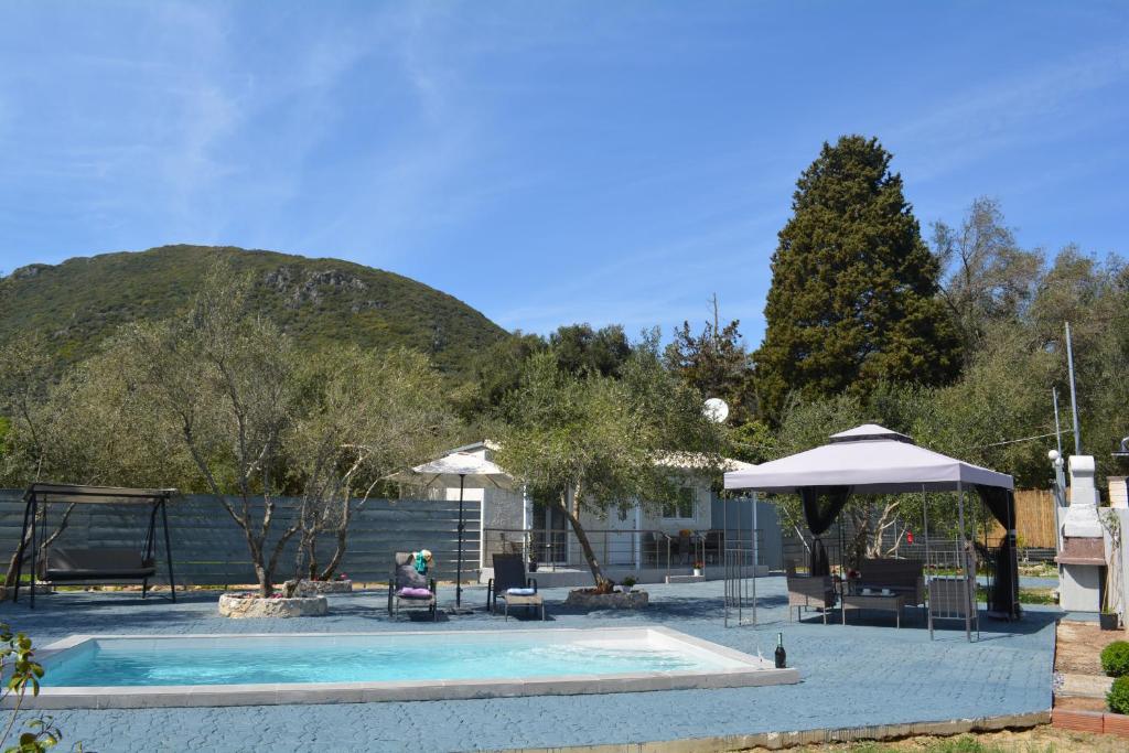 a pool with an umbrella and a person sitting next to it at Villa Gardiki for2 in Halikounas