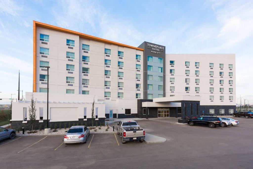 TownePlace Suites by Marriott Edmonton South في إيدمونتون: مبنى ابيض كبير به سيارات تقف في موقف للسيارات