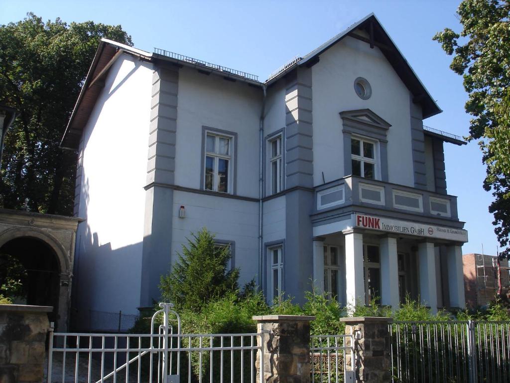 ein großes weißes Haus mit einem Zaun davor in der Unterkunft Ferienwohnung Funk in Berlin