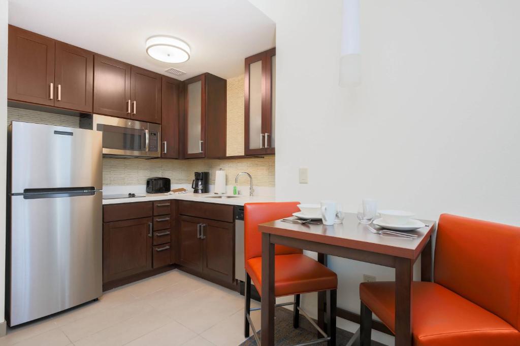 聖荷西的住宿－聖何塞機場萬豪旅館，厨房配有冰箱和带橙色椅子的桌子