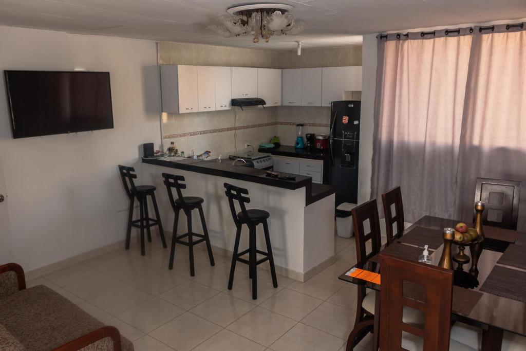 a kitchen with a counter and bar with chairs and a table at Apartamentos Vacacional Cartagena cerca Aeropuerto y Playa in Cartagena de Indias