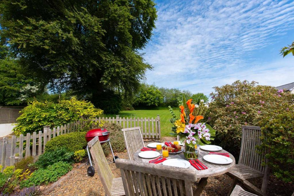 a table with plates and a vase of flowers on it at Ford Hill Cottage in East Down