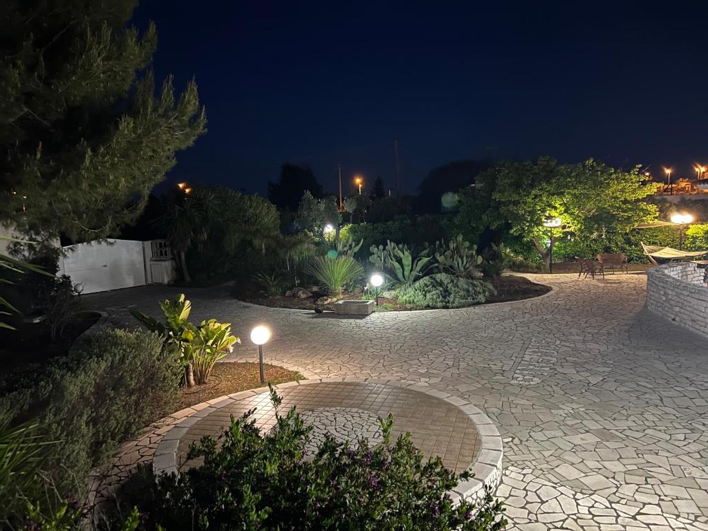 un jardín por la noche con una pasarela adoquinada en Villa Eugenia in Campomarino di Maruggio, Puglia - casa vacanze, en Campomarino
