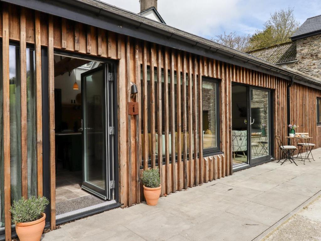 a wooden house with glass doors and potted plants at 1 Caddaford Barns in Buckfastleigh