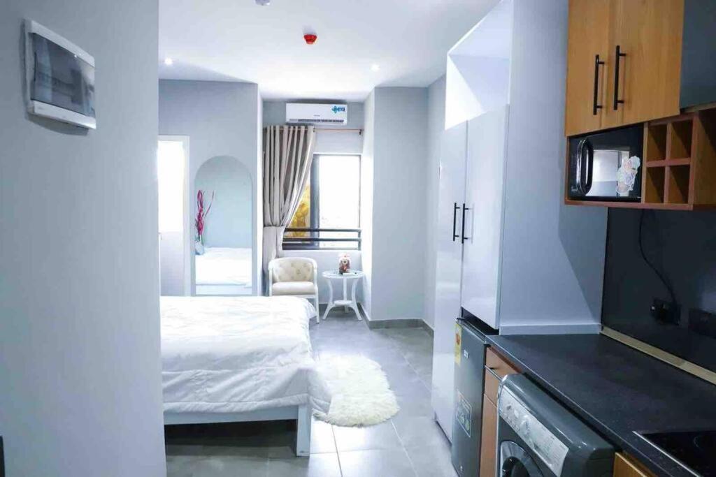 een kleine witte kamer met een bed en een keuken bij Sylz Residence Studio 1- 5 Mins from Labadi & Laboma Beaches in Accra