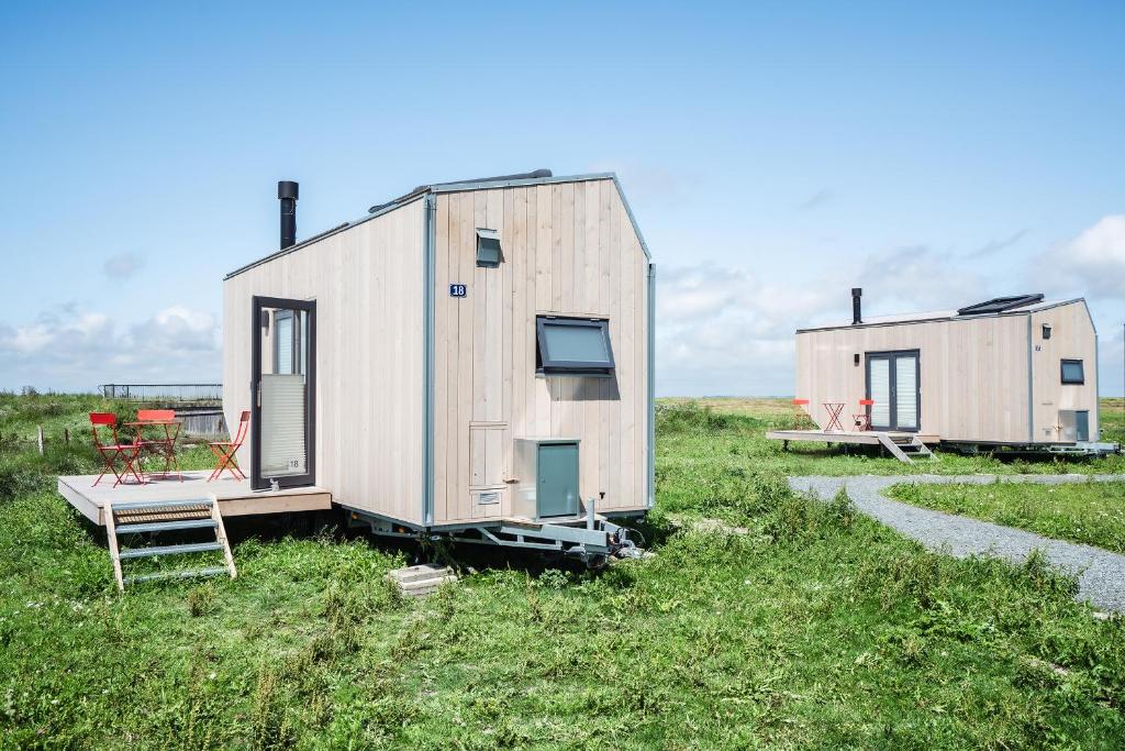 a couple of tiny houses sitting in a field at Tiny House Pioneer 19 Zur Meerseite - Green Tiny Village Harlesiel in Carolinensiel