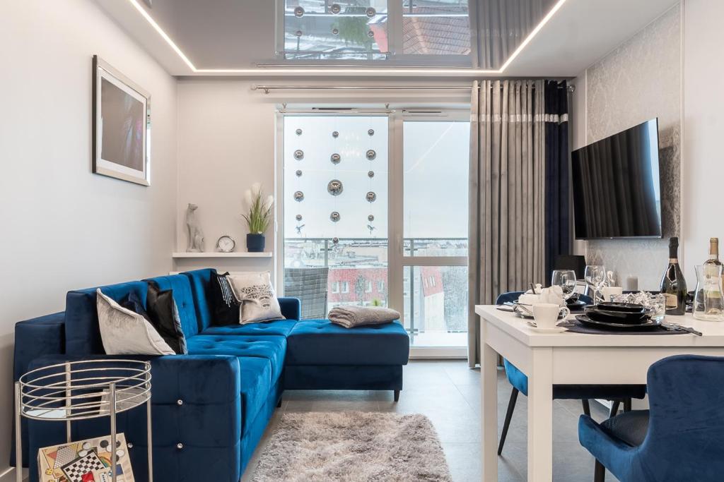 a living room with a blue couch and a table at Apartamenty Glamour Giżycko in Giżycko