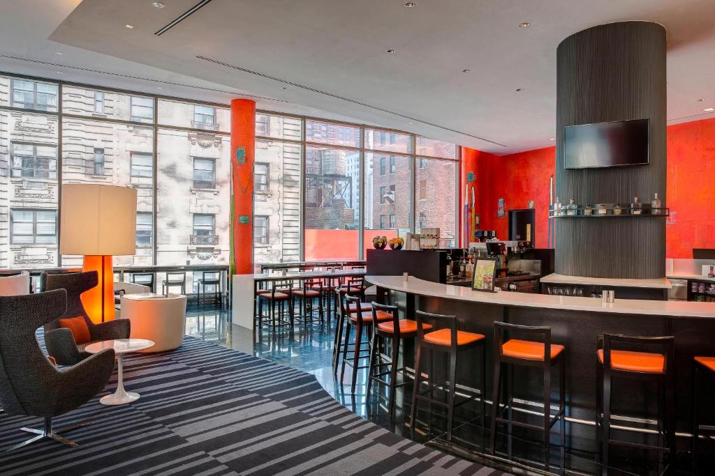 a lobby with a bar with orange walls and windows at Courtyard by Marriott New York Manhattan/Central Park in New York