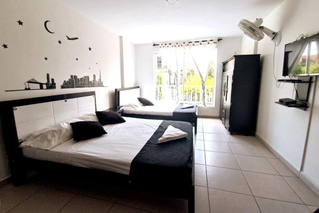 a bedroom with two beds and a large window at Casa al sur de Cali. Grupos/Familias/Deportistas! in Cali