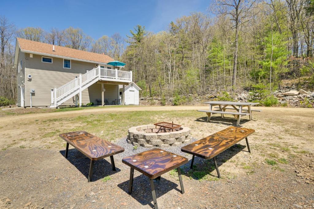 three picnic tables and a fire pit in front of a house at Woodsy Family Retreat 11 Mi to Raystown Lake! 