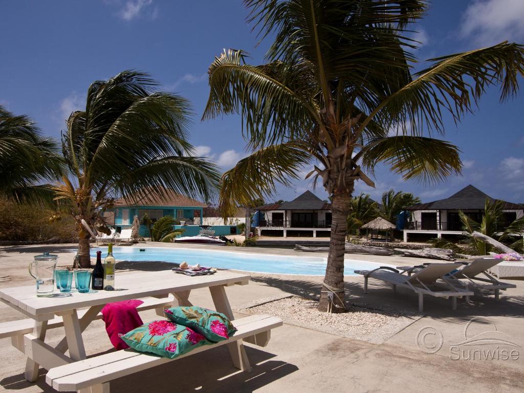a picnic table next to a swimming pool with palm trees at El Trupial in Kralendijk