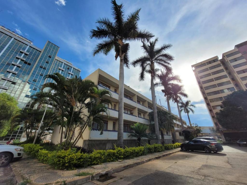 a car parked in front of a building with palm trees at Hotel Alvorada Taguatinga - Antigo Hotel Atlantico in Taguatinga