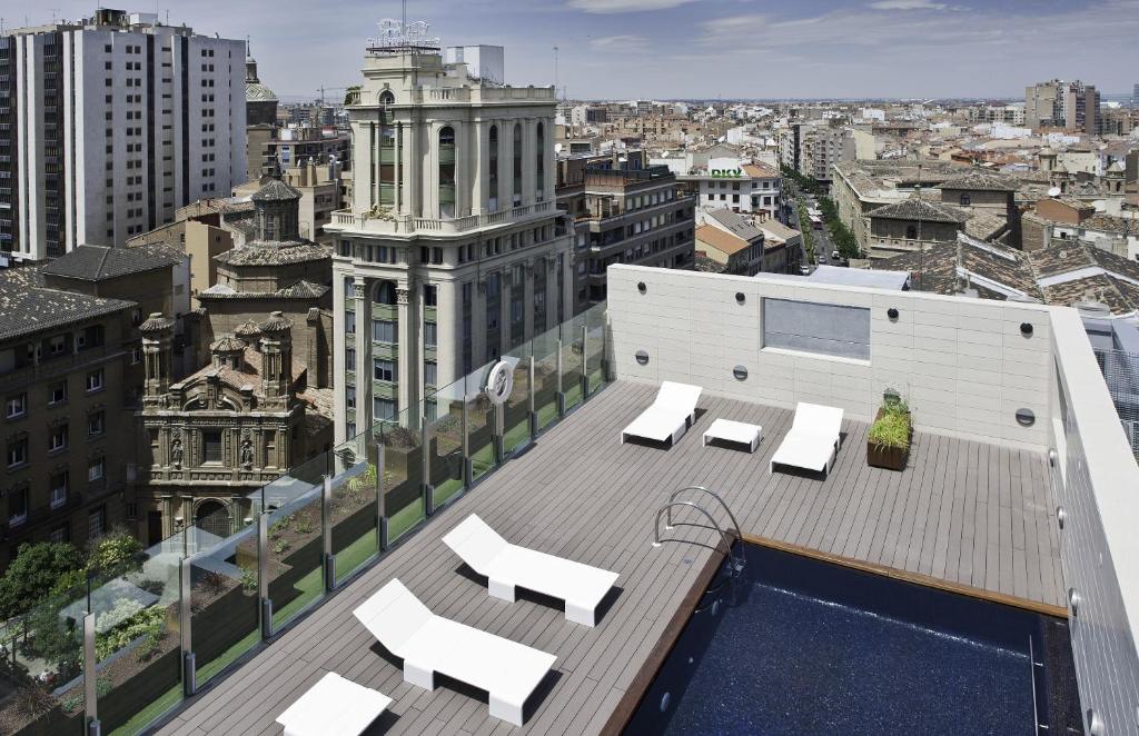 eine Dachterrasse mit Stühlen und ein Pool auf einem Gebäude in der Unterkunft Hotel Alfonso in Saragossa