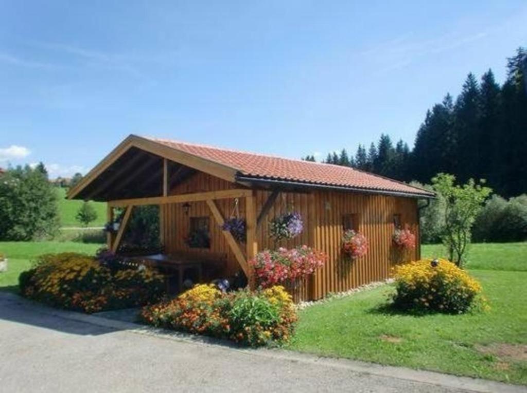 a small cabin with flowers in the grass at Ferienhaus in Röhrnbach mit Grill und Terrasse in Röhrnbach