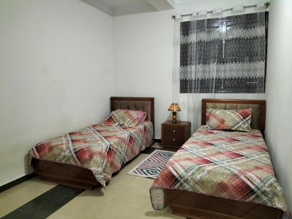 een slaapkamer met 2 bedden en een raam bij MAÏS in Alger