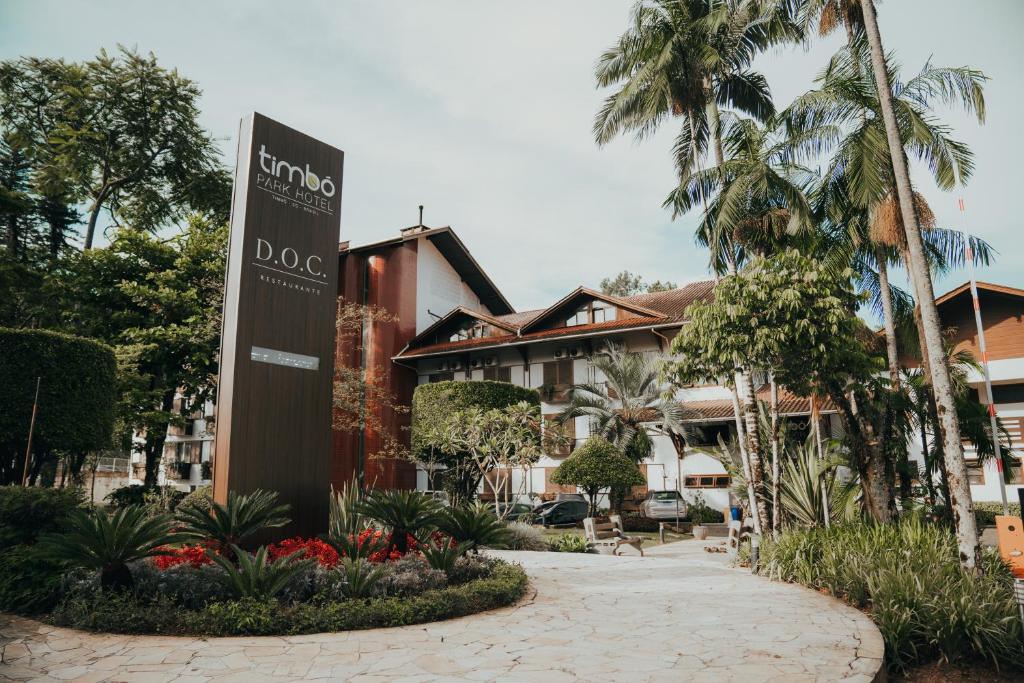 a sign in front of a building with palm trees at Timbó Park Hotel in Timbó