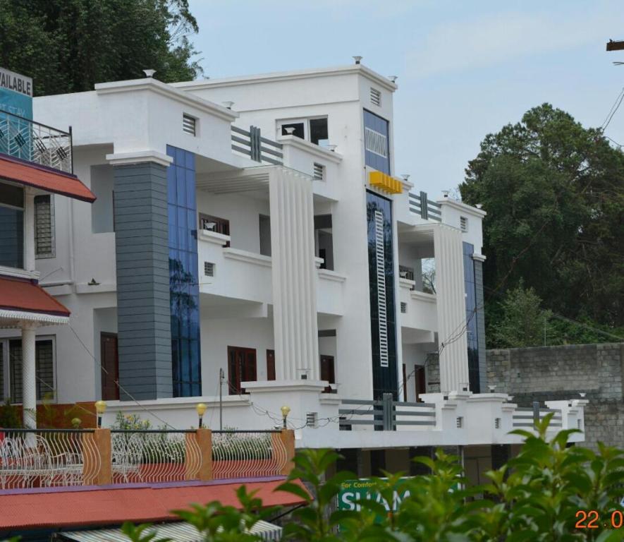 ein weißes Gebäude mit einem Schild davor in der Unterkunft Pinehill Suits in Udagamandalam