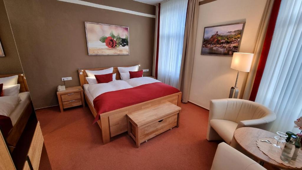 a hotel room with a bedroom with a bed and a chair at Gasthaus Pension Moselgruss in Dieblich