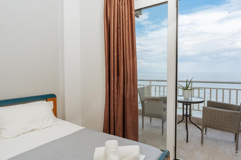 a bedroom with a bed and a balcony with a table at Hotel Galaxias in Paralia Katerinis