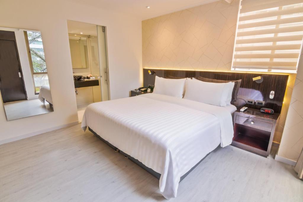 a large white bed in a room with a window at GHL Hotel Portón Medellín in Medellín