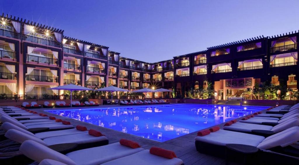 um hotel com piscina em frente a um edifício em Hôtel & Ryads Barrière Le Naoura em Marraquexe