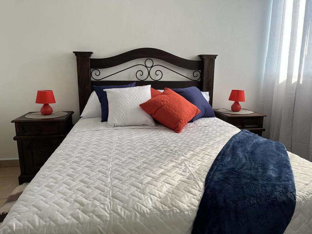 1 dormitorio con 1 cama con almohadas y 2 lámparas en Apartamento Tesoro-Ciudad de Guatemala zona 2 de Mixco en Guatemala