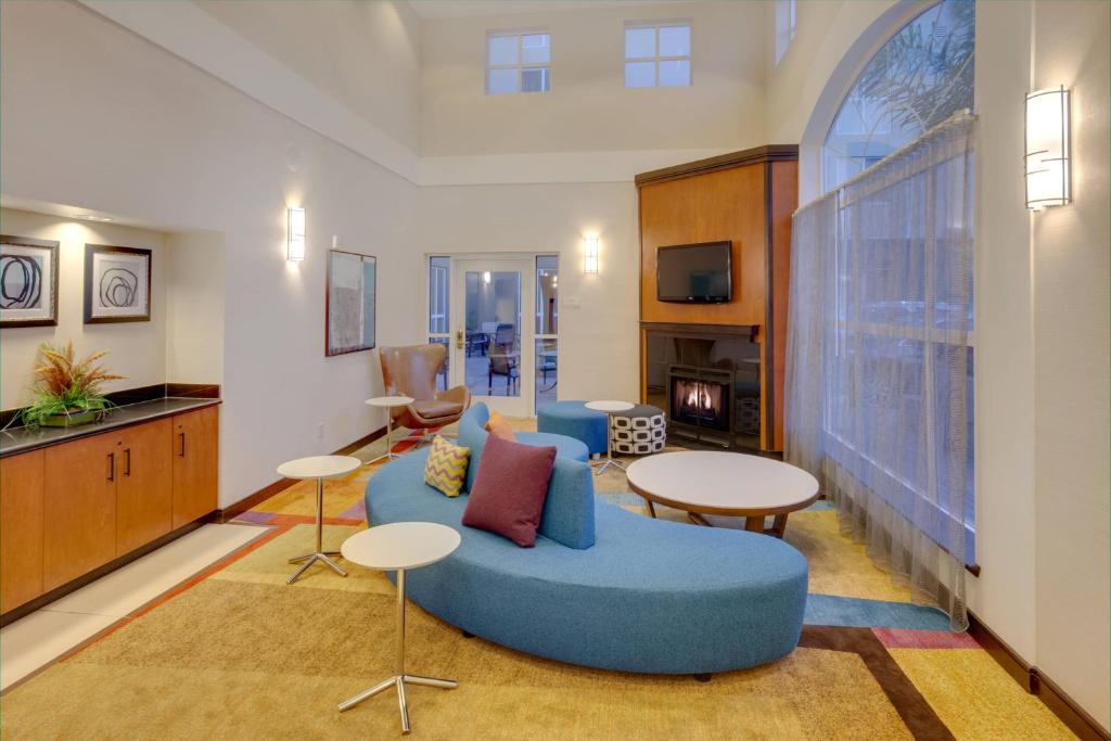 Fairfield Inn & Suites by Marriott San Francisco Airport في ميلبراي: غرفة معيشة مع أريكة زرقاء وطاولات