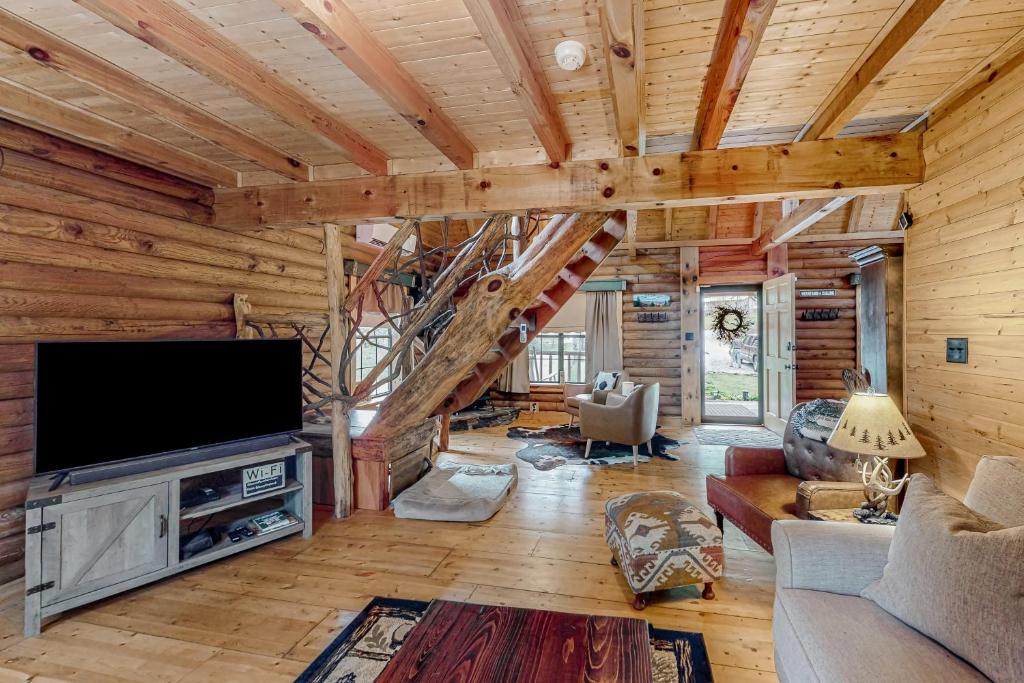 a log cabin living room with a large television and stairs at Glassy Mountain Getaway in Tiger