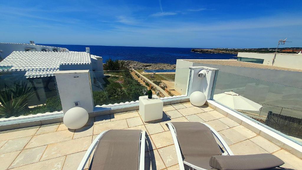 Un balcón con sillas y vistas al océano. en Binibeca Vell Luxury Villa, sea direct access, private pool en Binibeca