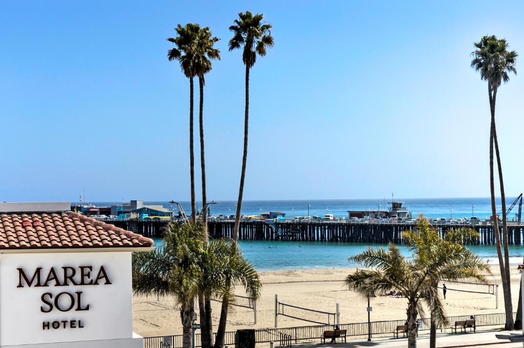 un cartello su una spiaggia con palme e un molo di Marea Sol Hotel a Santa Cruz
