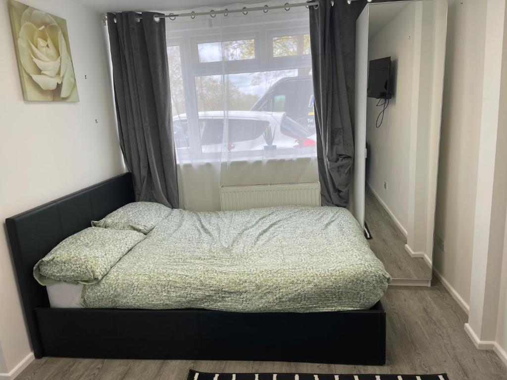 a bed in a room with a window and a mirror at En-suite room in central Milton Keynes in Milton Keynes