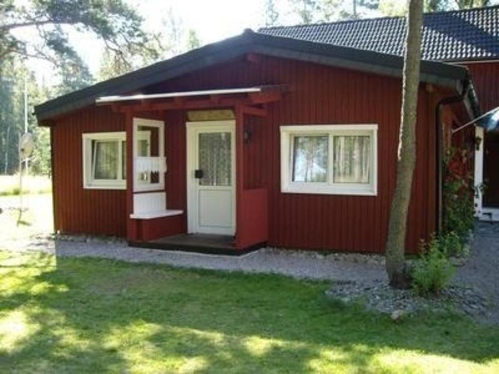 una casa roja con una puerta blanca y ventanas en Haus Cristina, en Ädelfors